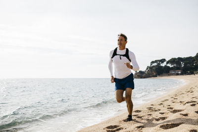 Full length of boy running on beach against clear sky