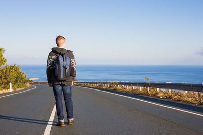 Rear view of man standing on road against sky