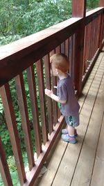 Full length of cute boy standing on railing