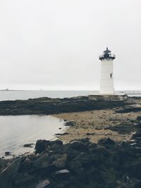 Lighthouse by sea against sky