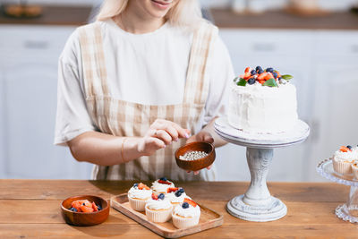 Midsection of woman making cake at home