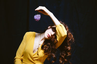 Young woman with arms raised hair against black background