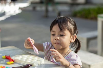 Close-up of cute girl playing with childs play clay at table outdoors