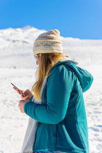 Woman in warm clothes while standing on snow covered land