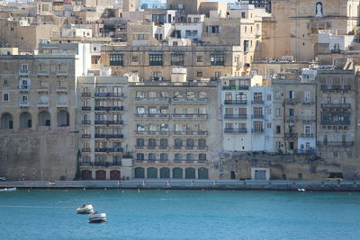 Boats in sea against buildings in city