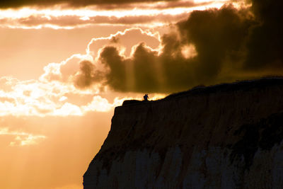 Silhouette of man standing on mountain against sky