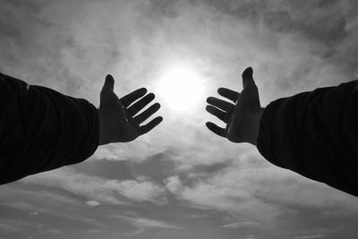 Low angle view of people hands against sky