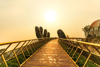 Footbridge against sky during sunset