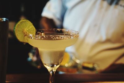 Midsection of man with cocktail on table in restaurant