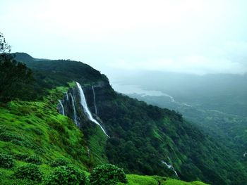 Scenic view of waterfall in forest against clear sky