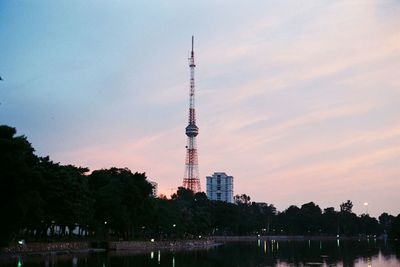 Communications tower in city against sky during sunset