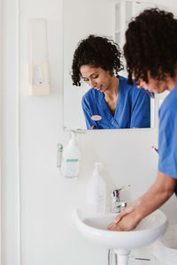 Female nurse washing hands at sink in hospital
