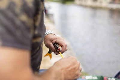 Midsection of man holding fish by river