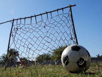 Close-up of soccer ball on field against sky