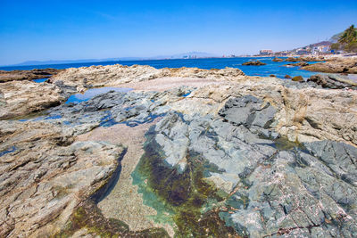 Rock formations on shore against blue sky