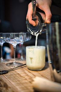 Cropped hand pouring drink on table