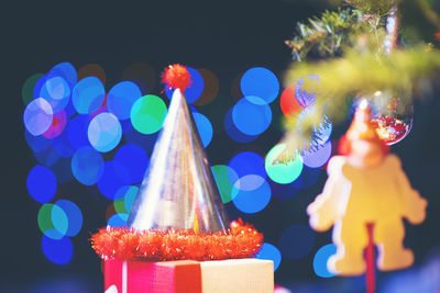 Close-up of party hat against illuminated christmas tree at night