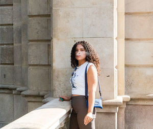 Portrait of young woman standing against wall
