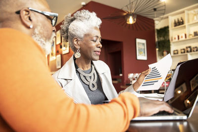 Male and female professionals looking at progress report in restaurant