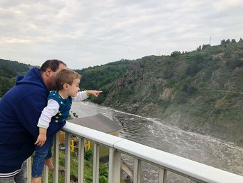 Man with son looking at river
