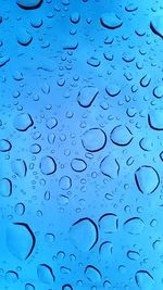 Full frame shot of raindrops on blue water