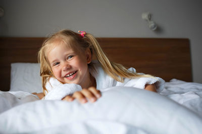 Portrait of smiling girl lying on bed at home