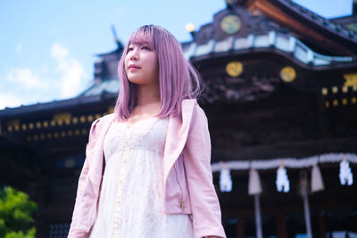 Portrait of young woman standing against illuminated city at night