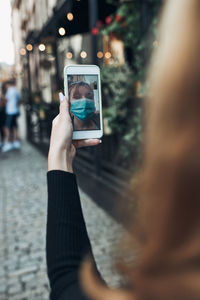 Woman wearing mask talking on video call outdoors