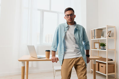 Portrait of young man using laptop at office