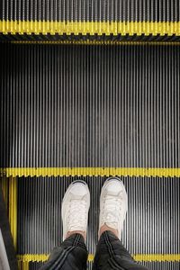 Low section of person standing on escalator