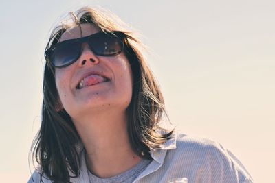 Close-up of young woman wearing sunglasses against clear sky