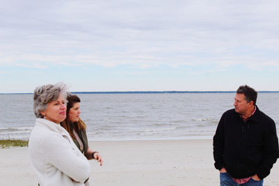 Friends standing on beach against sky