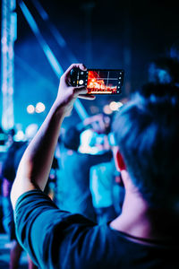 Close-up of man photographing music concert at night