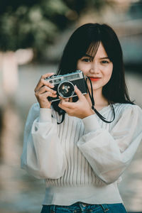 Portrait of a smiling young woman holding camera