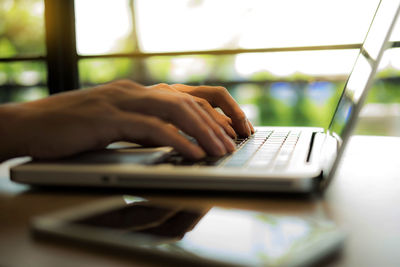 Cropped hands using laptop at table