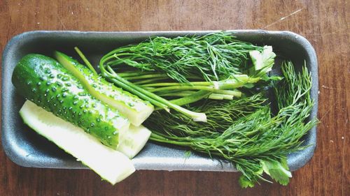 High angle view of dill and cucumber in container on table