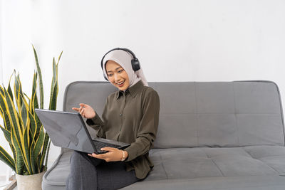 Portrait of woman using laptop while sitting on sofa