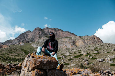 Man sitting on rock against mountains