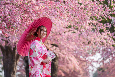 Woman standing by pink flower