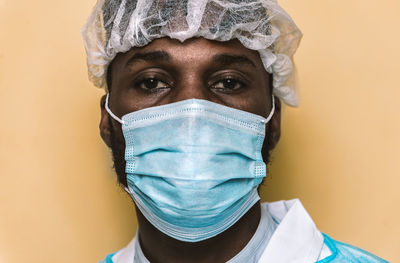 Portrait of doctor wearing mask standing against colored background