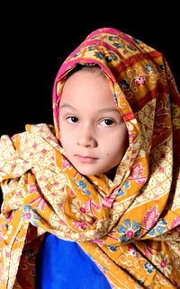 Portrait of cute girl against black background