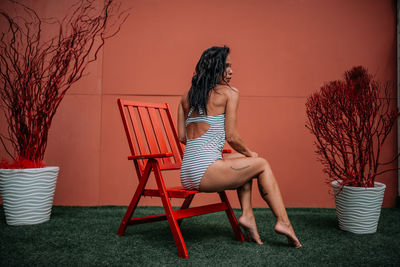 Woman sitting on chair against plants
