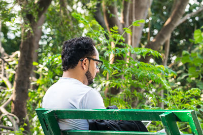 Man sitting on bench against trees at park