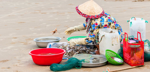 Woman cleaning fish while sitting at beach