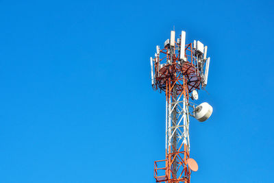 Low angle view of electricity pylon against clear blue sky