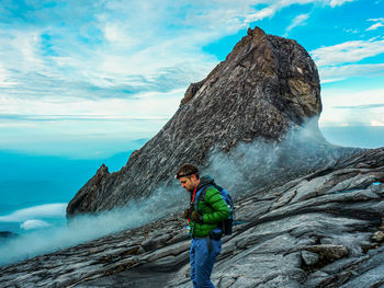 Man standing on rock against sky