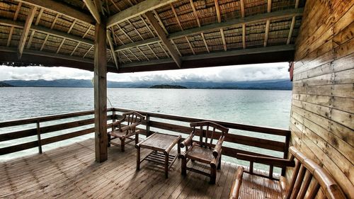 Chairs and table by sea against sky