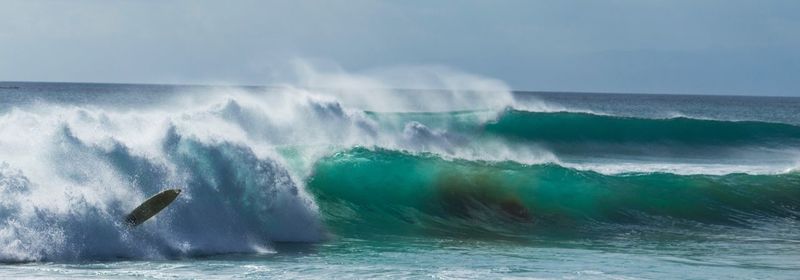 Waves splashing in sea against sky
