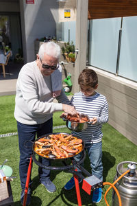 Grandfather and grandson preparing a paella in the garden