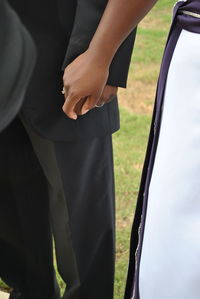 Midsection of couple holding hands while standing outdoors